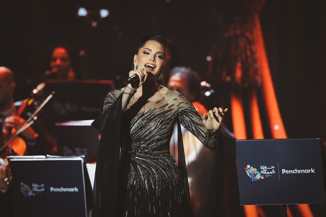  آمال على المسرح فستانا طويلا باللون الأسود، مصمم بأكمام طويلة من التل الشفاف المطرز