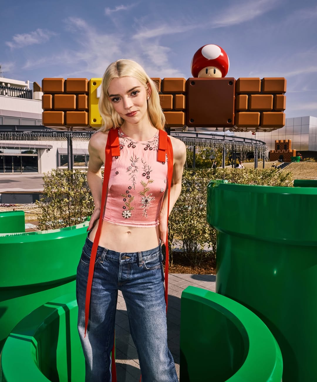 آنيا تايلور بصيحة بنطال الدنيم الداكن مع كروب توب حريري باللون الزهري