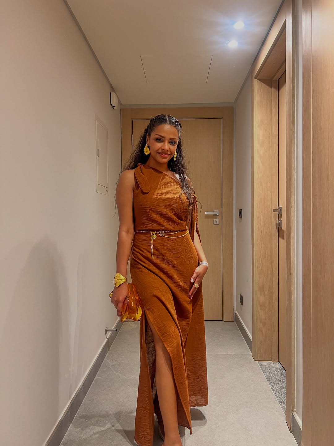 أسماء ترتدي فستانا طويلا باللون البني مصمم بكتف مائل