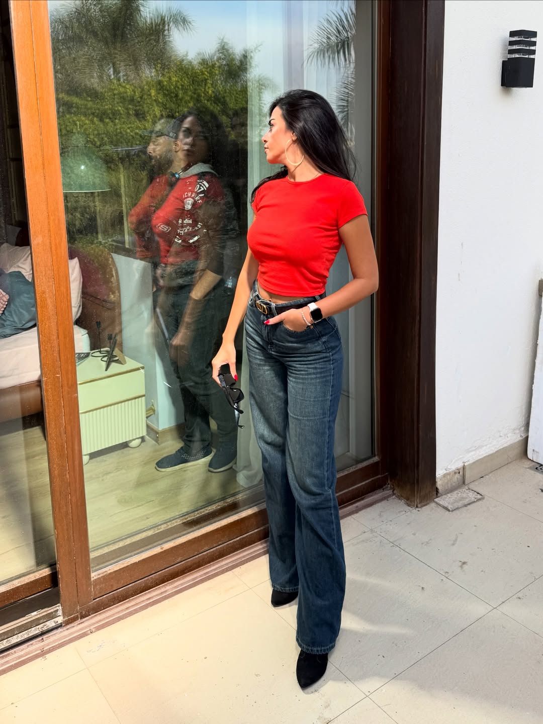 إلهام وجدي ببنطال الجينز الداكن وكروب توب باللون الأحمر الناري