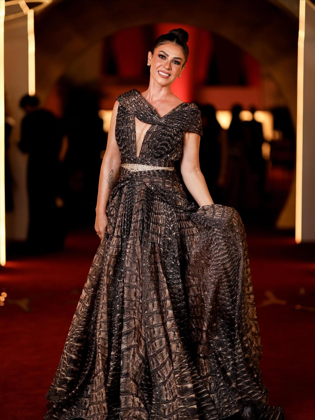 بسمة حسن فستانا بقصة حيوية لامعة بتصميم تغمره التطريزات الهندسية النافرة