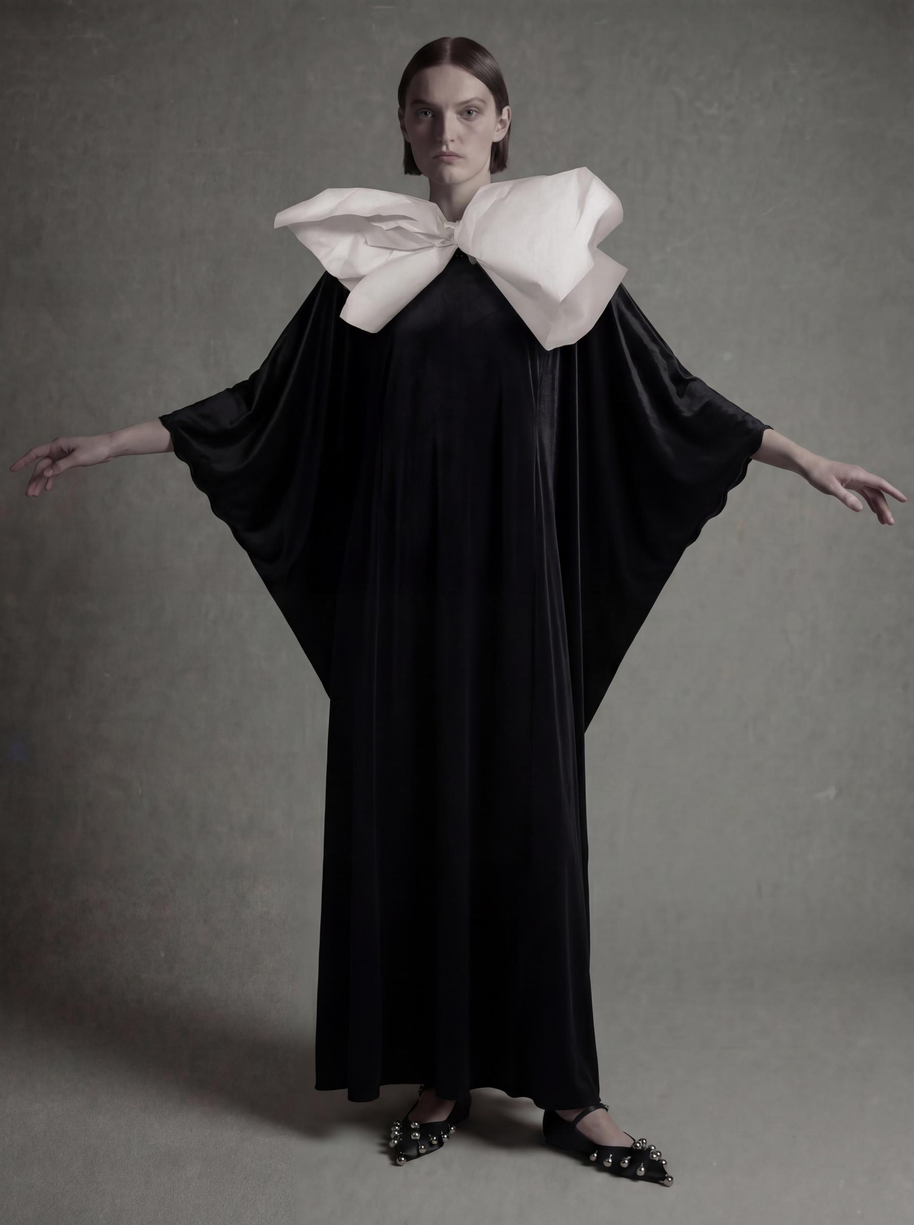 ثوب من الحرير الأسود مع عقدة كبيرة بيضاء عند الياقة من مجموعة رمضان 2026 من Atelier Hekayat
