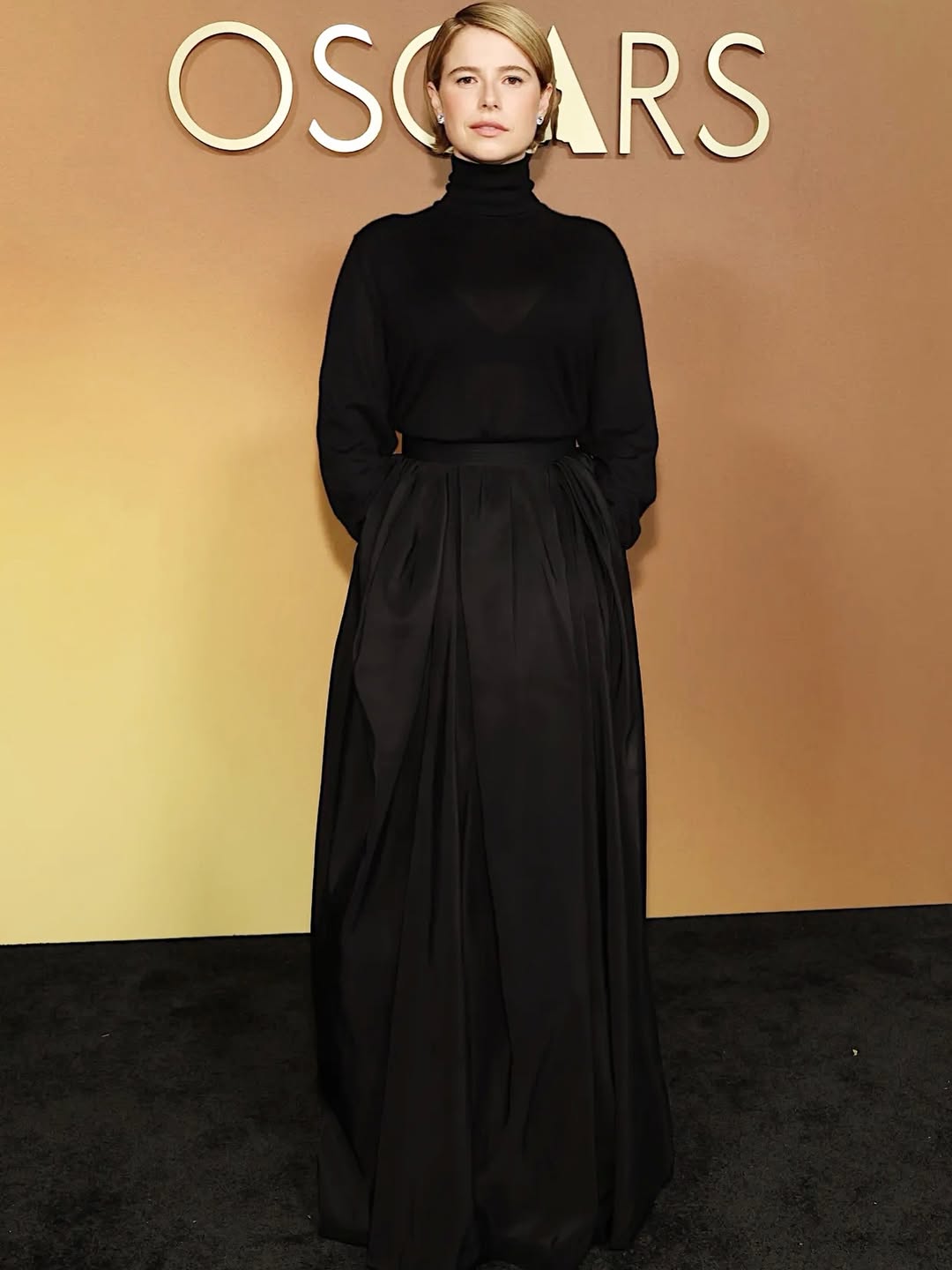 جيسي باكلي بإطلالة مونوكروم سوداء من تنورة منتفخة من الحرير الأسود بالخصر المحدد