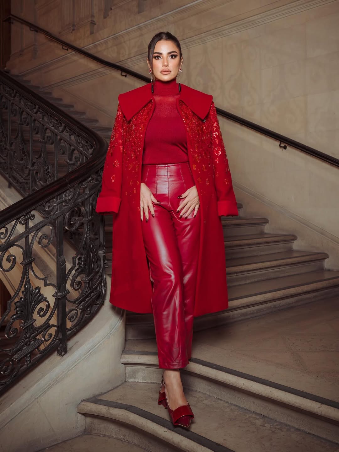 درة ببنطال الكاحل من الجلد الأحمر مع بلوفر يعلوه المعطف الصوفي بنفس اللون