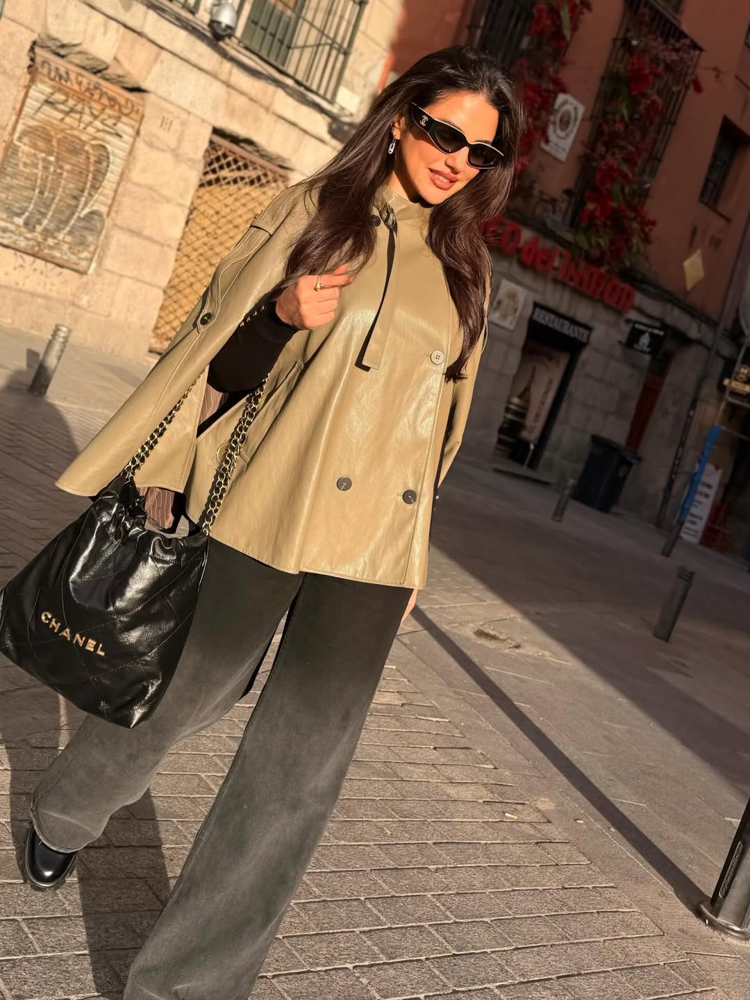 درة ببنطال من الدنيم الشاحب وبلوفر أسود وكاب من الجلد باللون البني