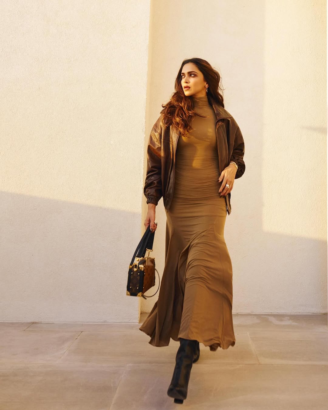 ديبيكا بادكون بالفستان الطويل باللون البني مع الجاكيت المنتفخ من الجلد البني