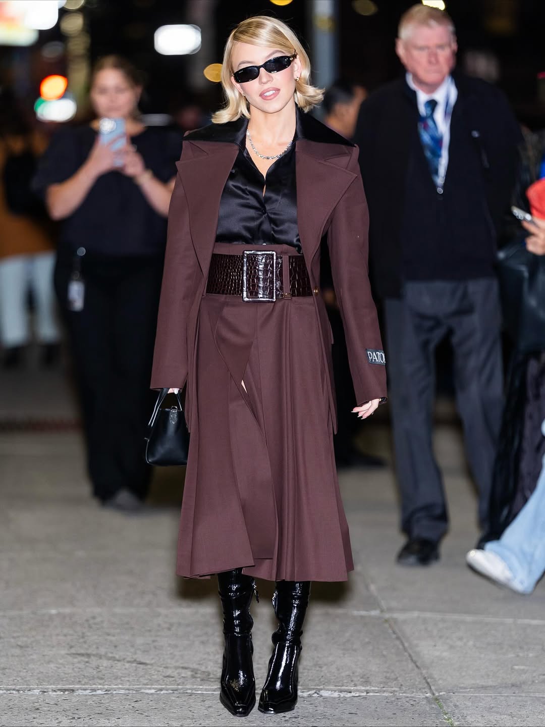 سيدني سويني بتنورة ميدي بكسرات البليسيه بشق طويل وجاكيت أوفر سايز