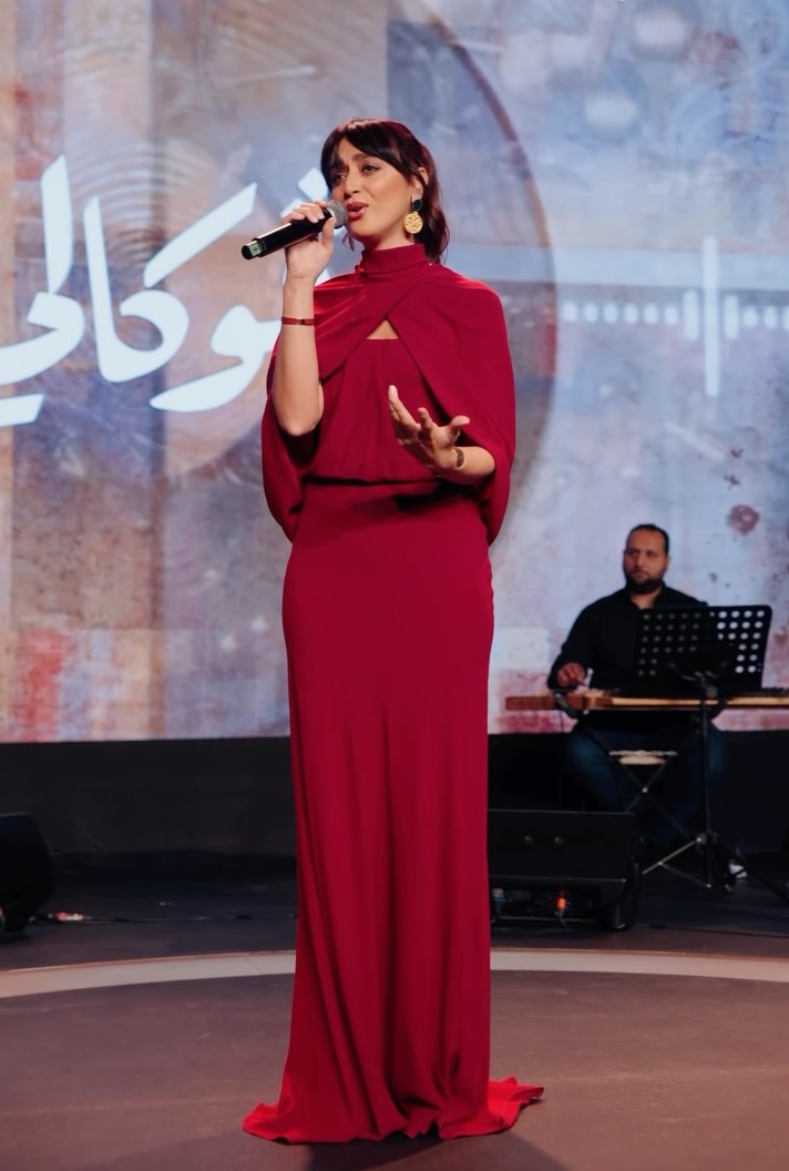 فايا يونان بثوب سهرة انسيابي باللون البرغندي مزود بكاب قصير