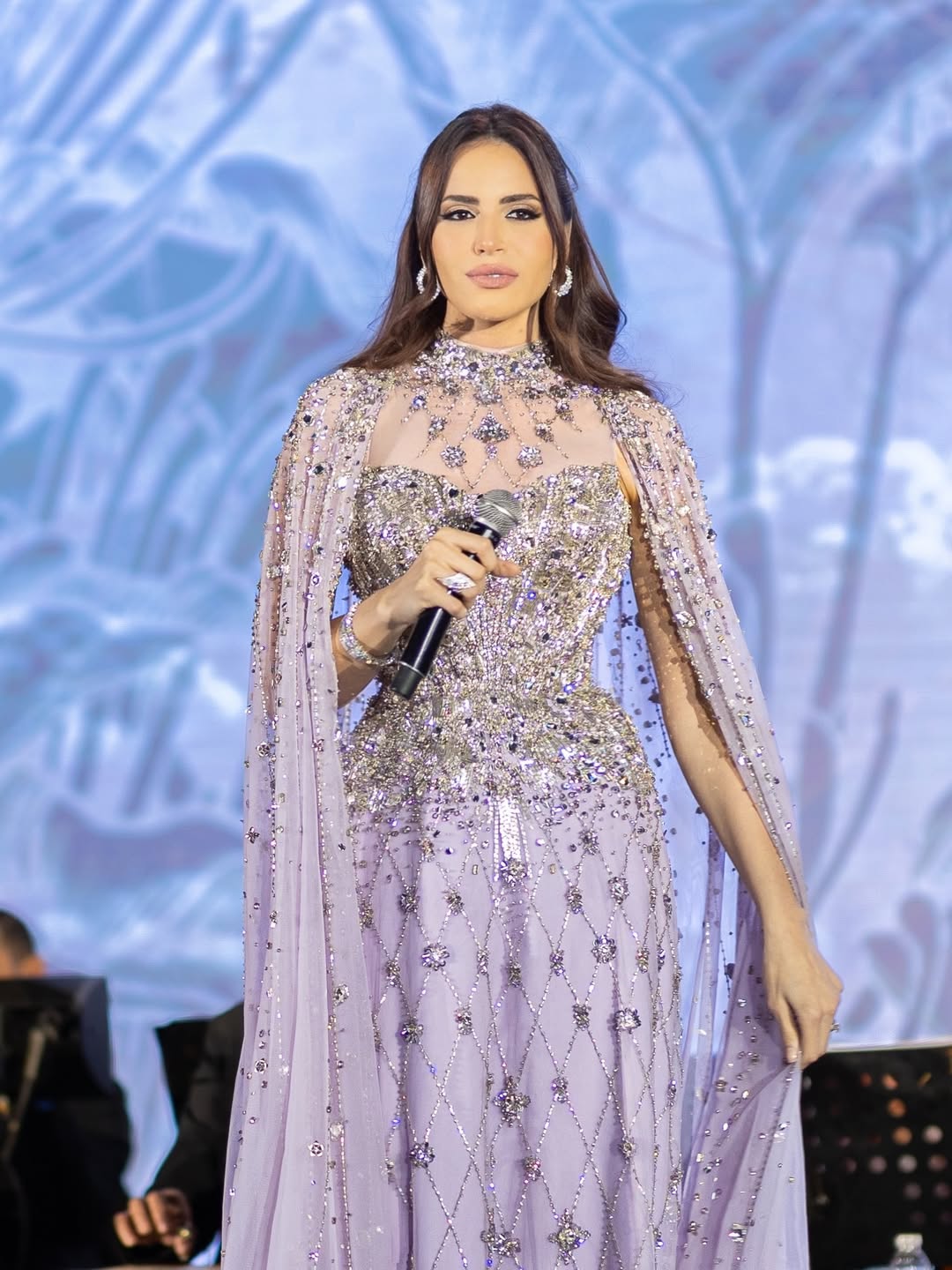 فستان آمال جاء مزوداً بكاب طويل منسدل فوق كتفيها بأسلوب وقور