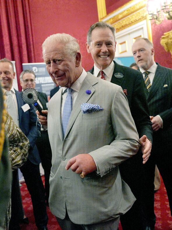قيمت في St James's Palace، شُوهد الملك تشارلز وهو يستعين بمساعديه الذين استخدموا المراوح المحمولة باليد لتلطيف الجو من حوله