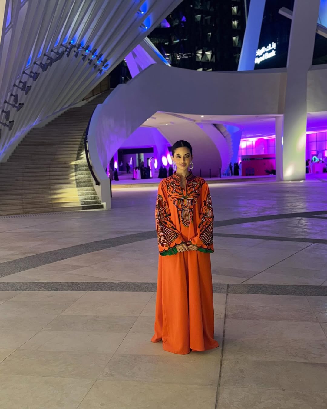 لمى الكناني مرتدية عباية طويلة باللون البرتقالي القوي