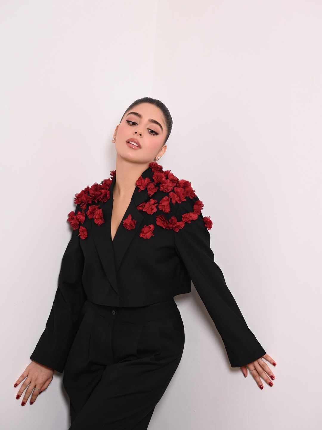 مايان السيد ببدلة باللون الأسود وجاكيت قصير زين بورود حمراء متفتحة