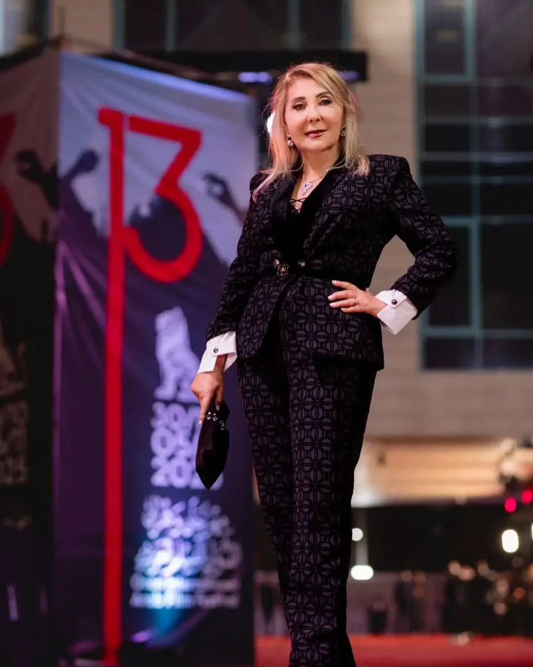 نادية الجندي ترتدي بدلة أنيقة باللون الأسود مطبوعة كليا بنقشة هندسية مكررة