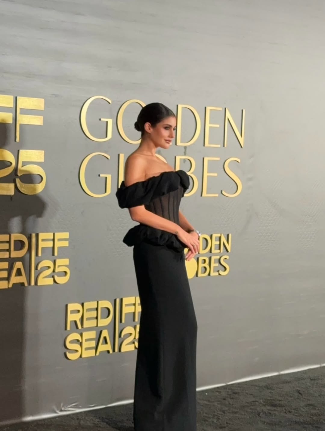 نور ترتدي فستانا طويلا بقصة الأوف شولدر ميزته أكتاف الكشكش المنسدلة