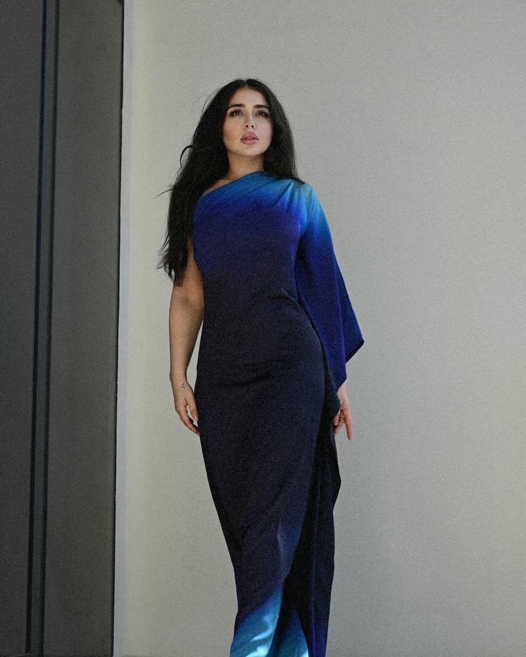 هيا بفستان طويل بتدرجات اللون الأزرق مصمم بقصة الكتف المائل،