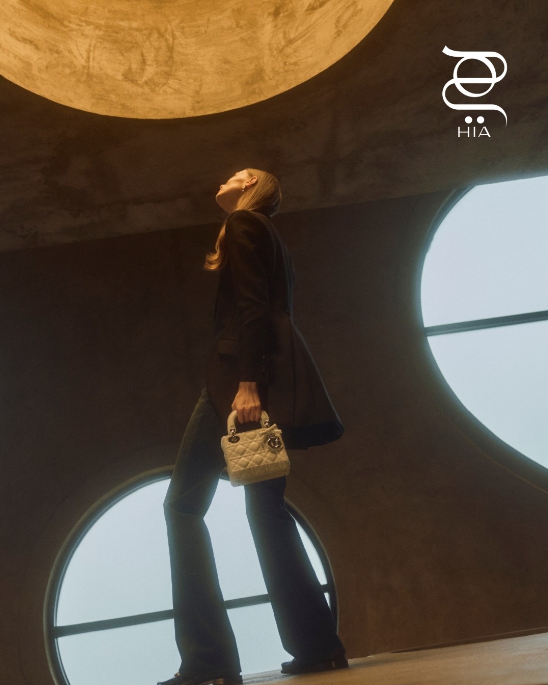 سترة سوداء وسروال دنيم وأقراط ‏ حذاء "ديور دربي دي" ‏Dior Derby D‏ باللون الأسود ‏ حقيبة "لايدي ديور" ‏Lady Dior‏ باللون ‏ الأزرق الفاتح مزدانة بعقدة ‏ جميعها من دار "ديور" ‏Dior