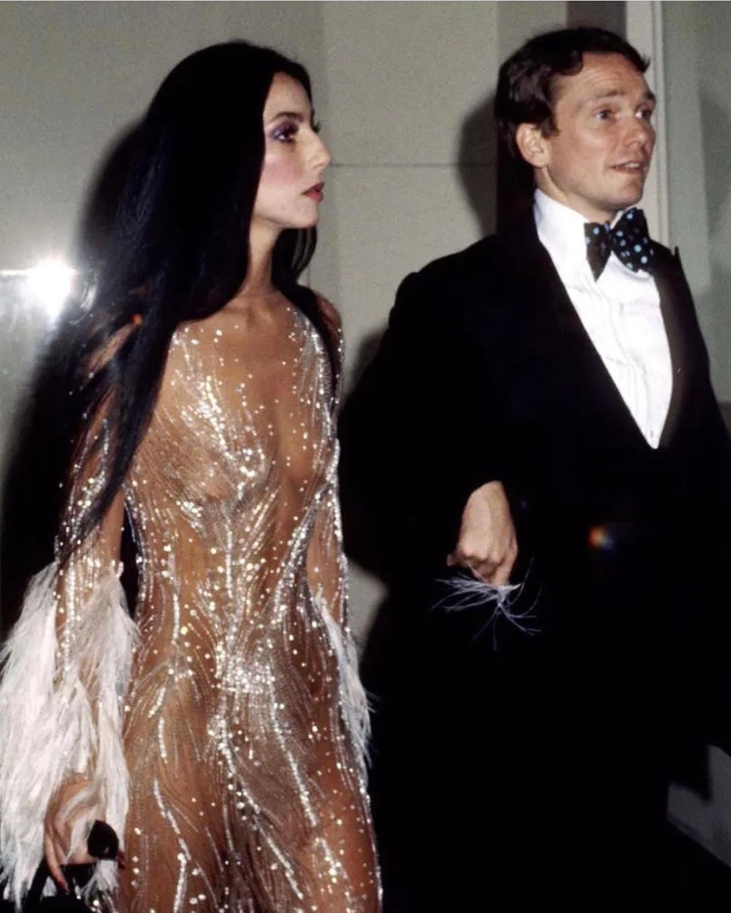 النجمة Cher في حفل "ميت غالا" عام 1974 برفقة بوب ماكي، وترتدي واحدة من أشهر تصميماته