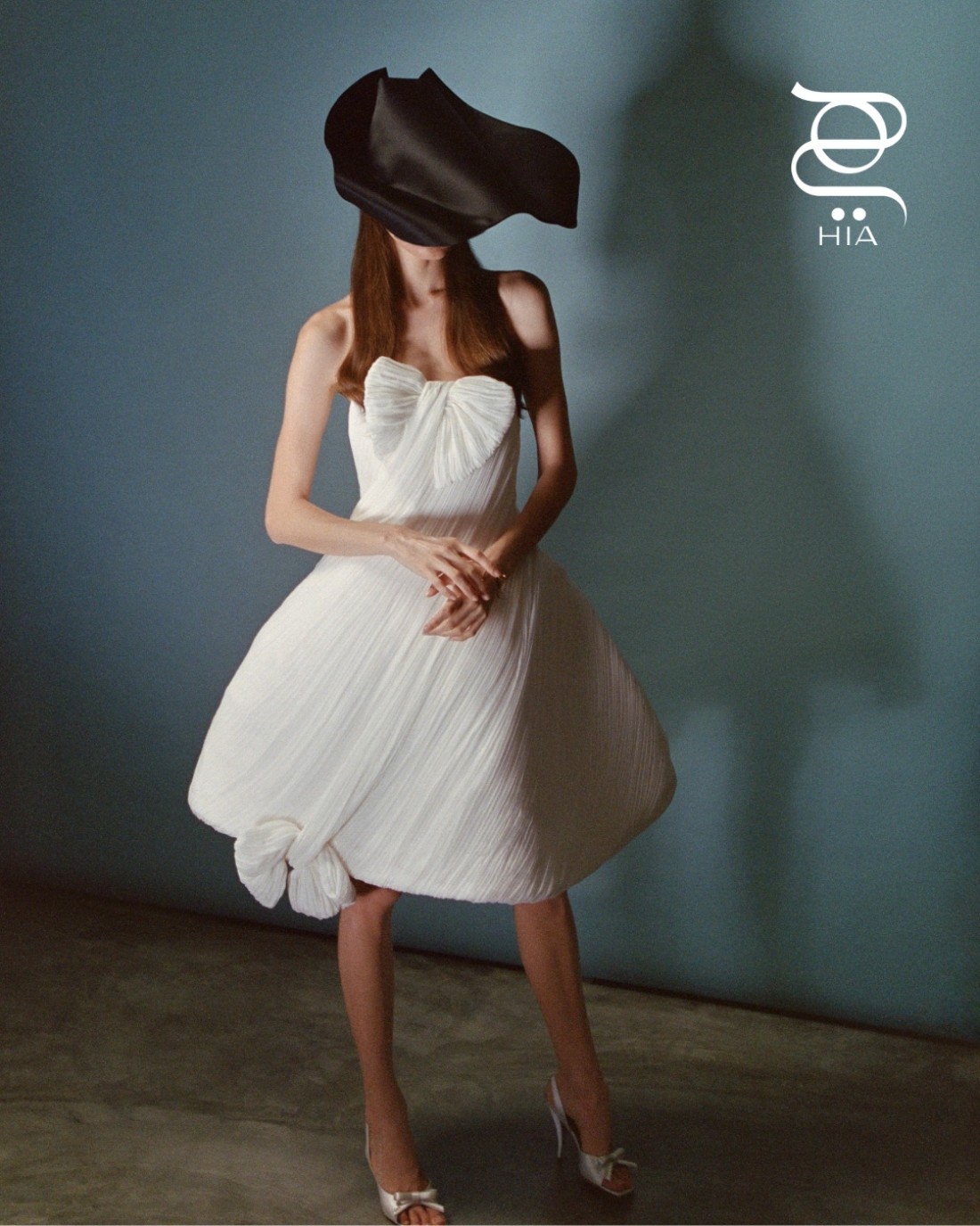 فستان أبيض مع قبعة "ديور شوو ستينغراي" ‏Dior Show Stingray صندل "ديور بوو" ‏Dior Bow‏ عالي الكعب جميعها من دار "ديور" ‏Dior