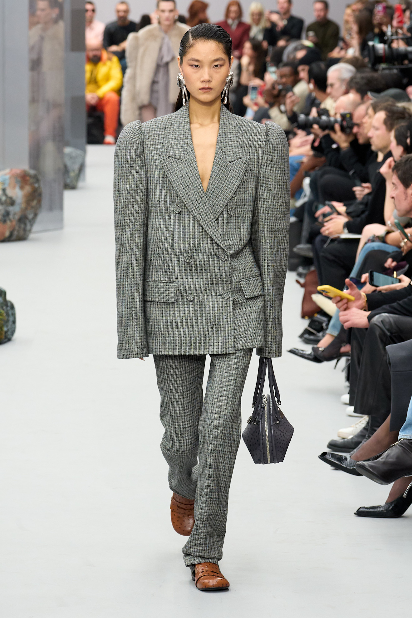 سترة دوبل بريستد مع سروال رمادي بنقشة المربعات من Acne Studios، تميّزت بأكمام منفوخة عند الكتفين تعكس روح الثمانينيات بلمسة عصرية جريئة