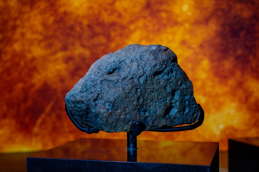 نيزك الشَّقّة 002  صخرة داكنة مائلة إلى الرمادي تُظهر قشرة الانصهار، وقد اكتُشفت خلال رحلة صقّارة شمال واحة جُغْبُوب.