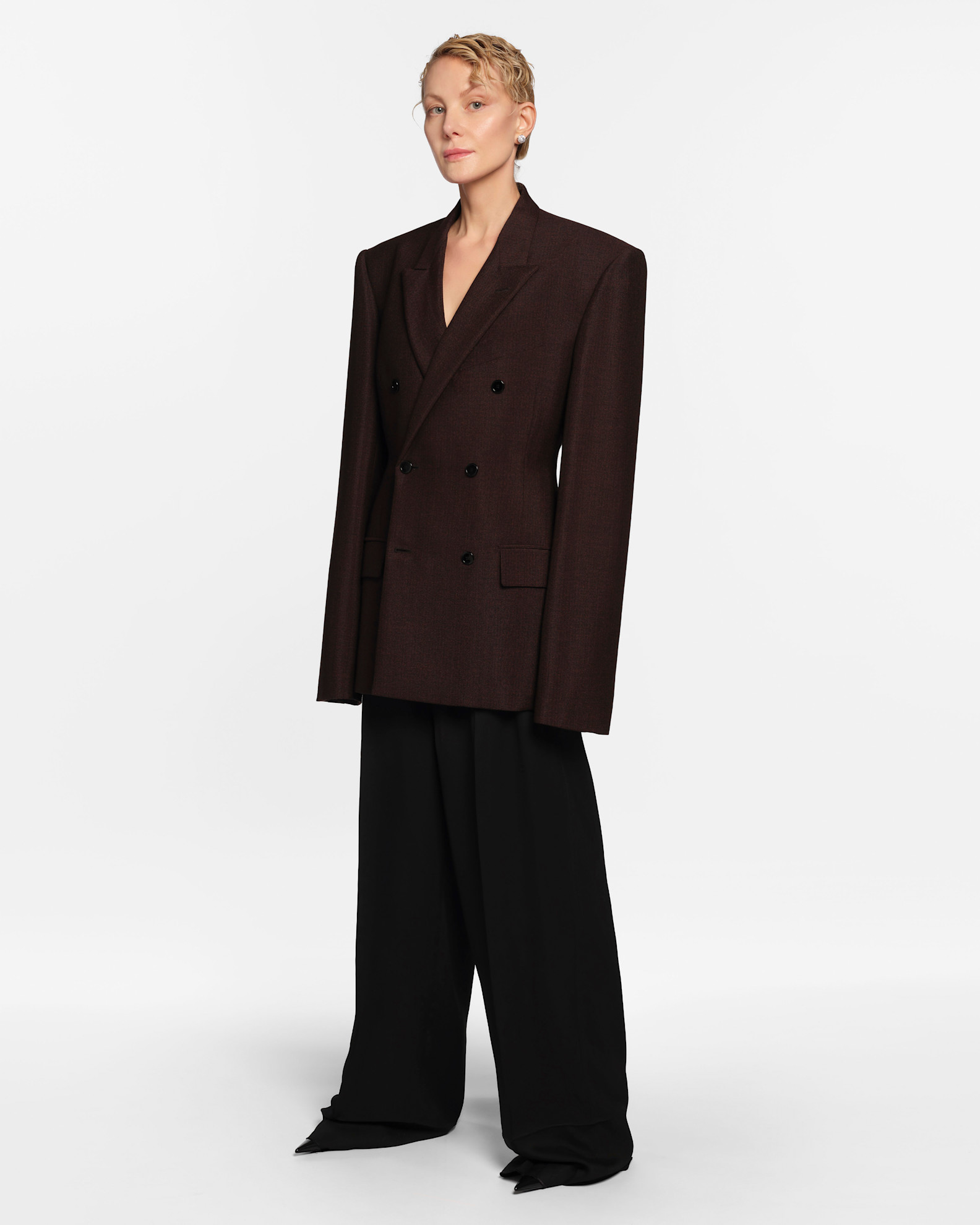 في مجموعات ريزورت 2026، برزت السترة الـ Double Breasted بأزرارها المزدوجة كقطعة أساسية لا غنى عنها في خزانة المرأة العصرية. لم تعد مجرد قطعة رسمية مرتبطة بالملابس الرجالية أو بالأناقة الكلاسيكية، بل تحوّلت إلى رمز للأناقة القوية والأنثوية في آن واحد. هذا الموسم، قدّم المصمّمون السترة بروح معاصرة، مع مراعاة التفاصيل الدقيقة مثل الأزرار الكبيرة، القصّات المدروسة، والأكتاف المصمّمة لتمنح حجمًا متوازنًا للإطلالة. بفضل هذه التعديلات، لم تعد السترة مجرد قطعة عادية، بل باتت عنصرًا يحدّد شخصية الإطلالة ويمنحها حضورًا واثقًا وقويًا، سواء في المناسبات الرسمية أو الإطلالات اليومية.  يتيح التصميم المزدوج للأزرار مرونة غير محدودة في التنسيق، فيمكن اعتمادها بقصّة واسعة Oversized لإطلالة عفوية وجريئة، أو محددة عند الخصر لإبراز القوام وإضفاء لمسة أنثوية متقنة. كما ساهمت الألوان الحيادية مثل الأسود، البني، والعاجي في تعزيز الطابع الاستثماري لهذه السترة، فهي قطعة تدوم عبر المواسم وتتناغم بسهولة مع مختلف القطع الأخرى، من الفساتين الحريرية إلى السراويل الكلاسيكية، أو حتى مع الإكسسوارات العصرية لإطلالة محدثة.  إن الاستثمار في هذه السترة لا يقتصر على الموسم الحالي، بل هو خيار طويل الأمد يضيف قيمة حقيقية لأي خزانة تبحث عن الأناقة الذكية والمتجددة.  عودة القَصّات القوية بروح معاصرة  برزت السترة ذات الأزرار المزدوجة بقصّات واضحة المعالم، توازن بين البنية الصارمة والراحة العملية. الأكتاف العريضة، الطول المدروس، والقصّات الواسعة أحيانًا، أعطت هذه القطعة بعدًا حديثًا يواكب أسلوب الحياة اليومي، من دون أن يفقدها طابعها الكلاسيكي. صورة سترة Double Breasted باللون البني وبقصة Oversized من بالنسياغا، تعكس القوة بأسلوب عصري جريء  الخطوط المقلّمة… أناقة لا تزول  النقشات المقلّمة لعبت دورًا أساسيًا في إبراز هذه الصيحة، إذ منحت السترة طابعًا كلاسيكيًا متجدّدًا يذكّر بأناقة التسعينيات ولكن بروح أكثر حداثة. الخطوط العمودية، على وجه الخصوص، أضافت طولًا وانسيابية للإطلالة. صورة سترة سوداء مقلّمة من فندي، تجسّد التوازن بين الرسمية والرقي العصري  الـ Oversized… حين تلتقي الراحة بالأناقة  لم تغب القصّات الواسعة عن منصات ريزورت 2026، حيث برزت سترات Double Breasted بحجم أكبر من المعتاد، ما أضفى على الإطلالة لمسة عفوية وعصرية. هذا الأسلوب يسمح بتنسيق السترة م