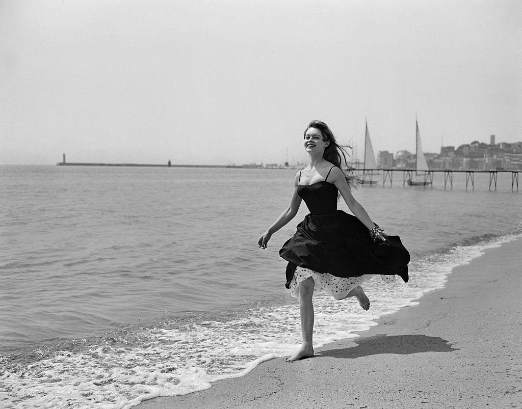 الممثلة الفرنسية بريجيت باردو تركض على رمال مدينة كان الفرنسية عام 1956 (الصورة من Getty) 