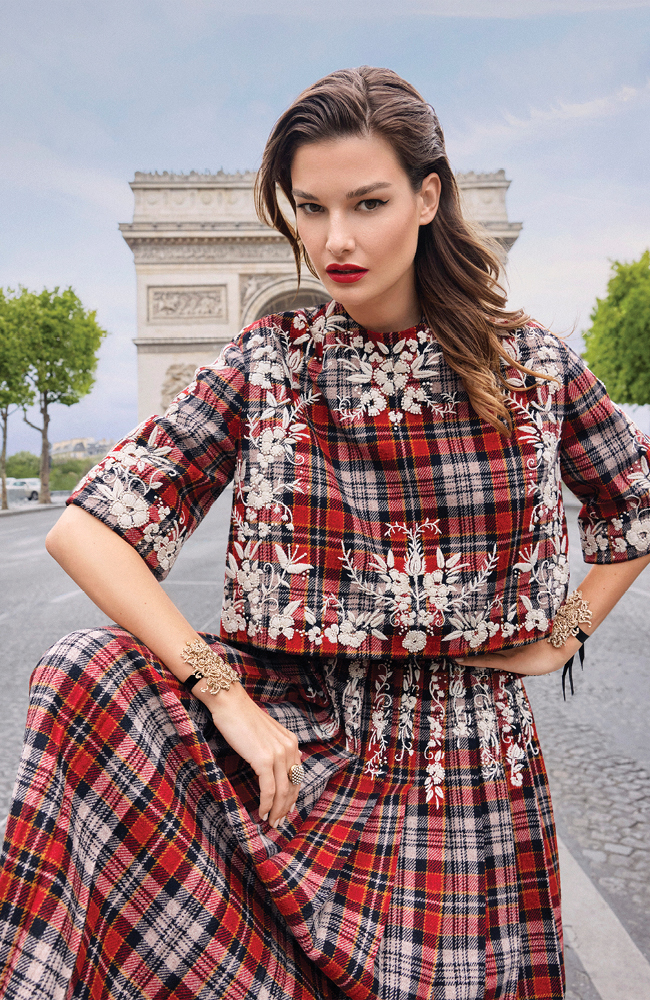 من "ديور هوت كوتور" Dior Haute Couture، قميص من الطرطان المطرز، وتنورة مثنية مطابقة، وسواران من شريط ترصعه زخرفة على شكل شارة رسمية، وخاتم.