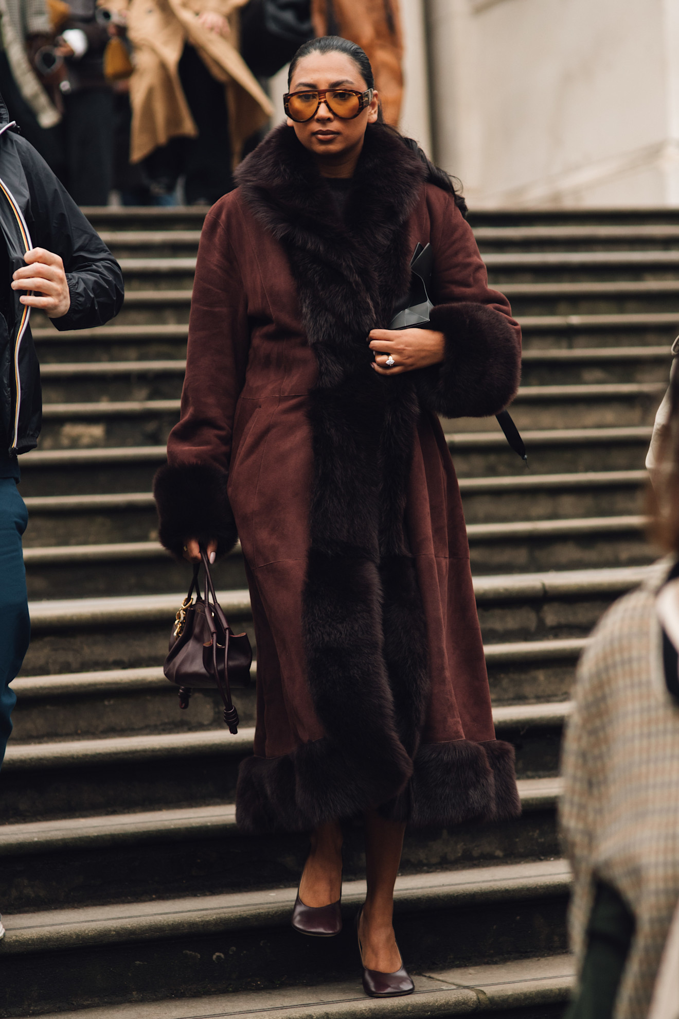 معطف بني طويل بالفرو يفرض حضوره على الشارع بقوة، ويمنح أي إطلالة لمسة من الفخامة والجاذبية التي لا يمكن تجاهلها.