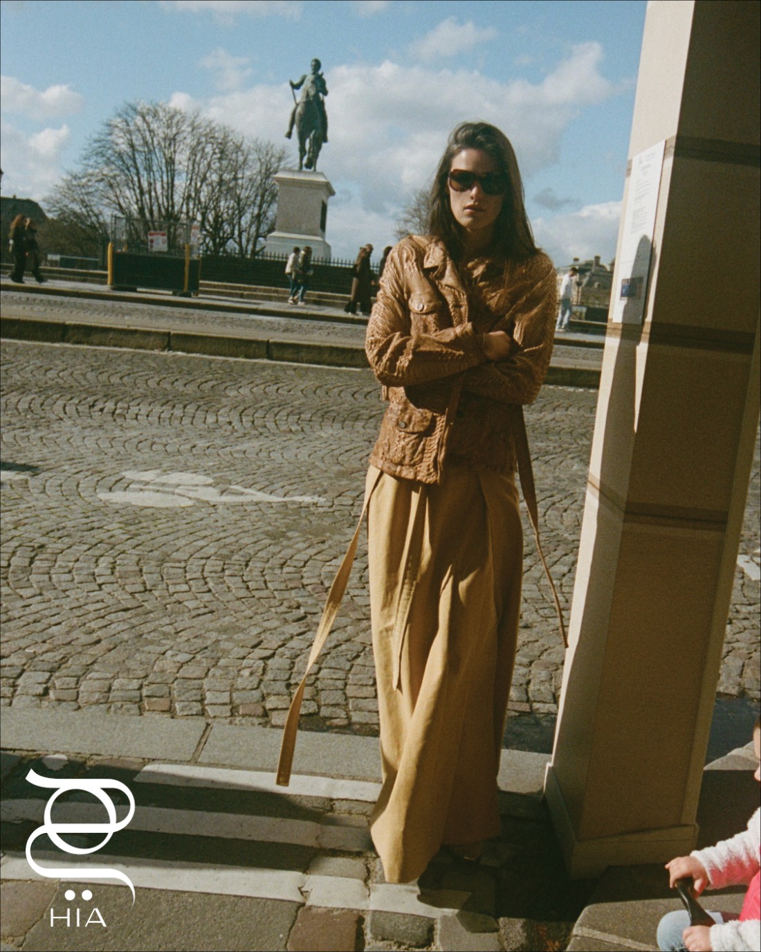 سترة من "برادا" ‏Prada، تنورة من "سيلين" ‏Celine، وقميص من "بوتيغا فينيتا" ‏Bottega Veneta، ‏ وحذاء من "إيزابيل مارانت" ‏ISABEL MARANT، ونظارات شمسية من "شانيل" ‏Chanel