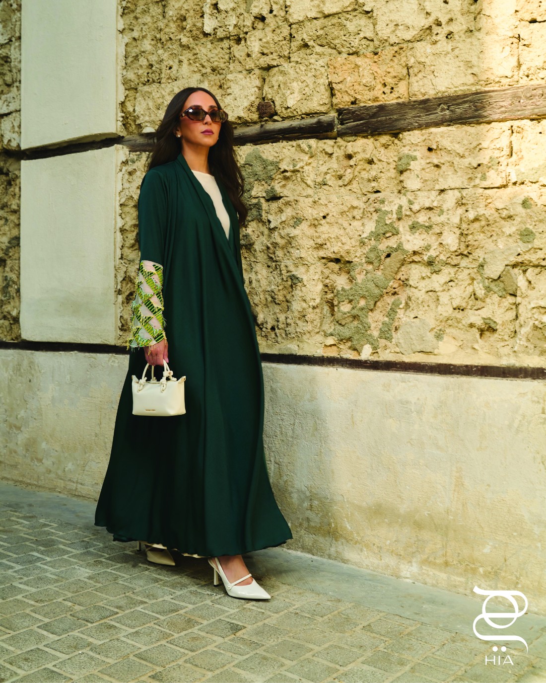 عباية من سماح خاشقجي Samah Khashoggi، حذاء كعب عالي Slingback مدبب مزين بإبزيم لؤلؤي "هيلينا" Helena بلون Chalk، وحقيبة Tote بمقبض معقود "سامي" Sammie بلون كريمي، جميعها من "تشارلز آند كيث" Charles & Keith