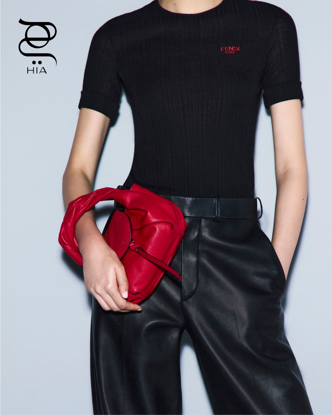 سترة صوفية باللون الأسود، سروال جلدي أسود، وحقيبة “ميني سباي" Mini Spy صغيرة باللون الأحمر، جميعها من “فندي" Fendi