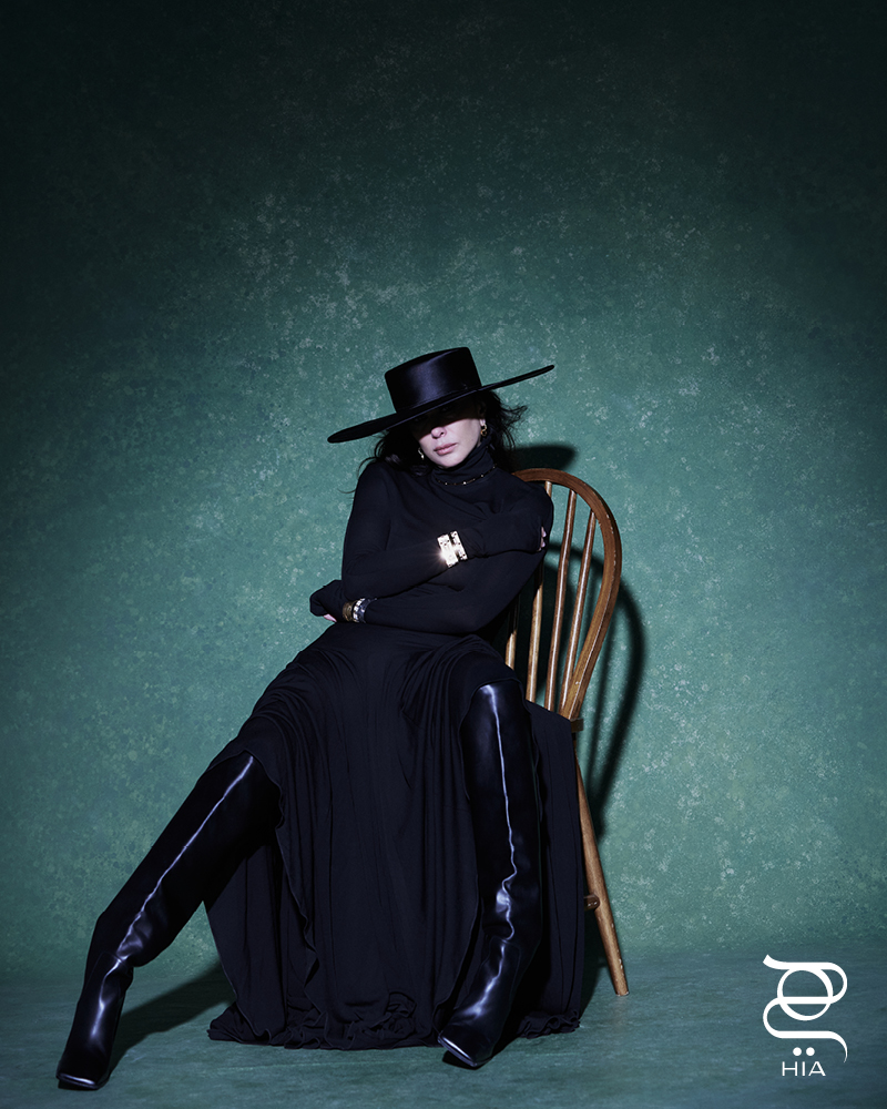 أقراط أذن مزدوجة LOVE بالذهب الأصفر، أساور LOVE UNLIMITED بالذهب الأصفر وبالذهب الأبيض، أساور LOVE بالذهب الأبيض والماس، جميع المجوهرات من "كارتييه" CARTIER فستان طويل وجزمة عالية الساق من "علية" Alaia، قيعة واسعة من "كريستينا فيديلسكايا" Kristina Fidelskaya