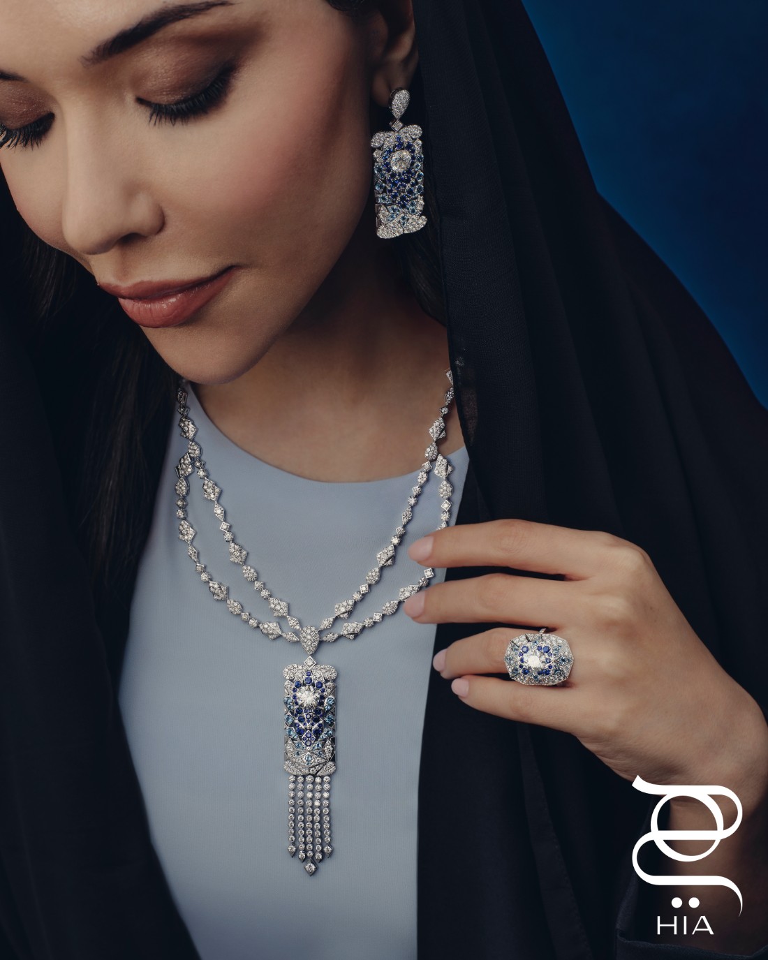 من طقم TAJ MAHAL من مجموعة المجوهرات الراقية ILLUMINATED WONDERS: عقد وخاتم وأقراط أذن مرصعة بالماس والصفير الأزرق والأكوامارين الأزرق، جميع المجوهرات من "معوّض" MOUAWAD عباءة وشيلة من "سيرب" SERRB