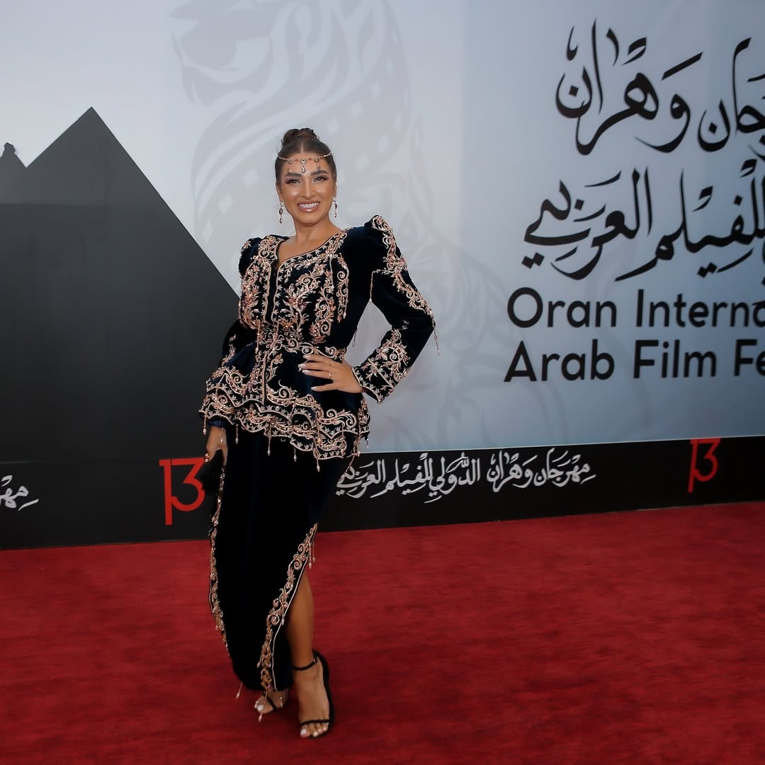 روجينا بالتنورة مرفقة بجاكيت بأكتاف منتفخة وحواف من الكشكش بقصة الكلوش