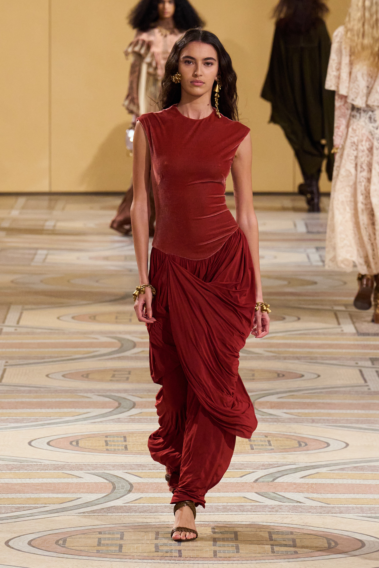 فستان من "زيميرمان" Zimmermann بقماش الفلور الأحمر بطيات مميزة وخصر منخفض يمنح الإطلالة طابعًا رومانسيًا معاصرًا