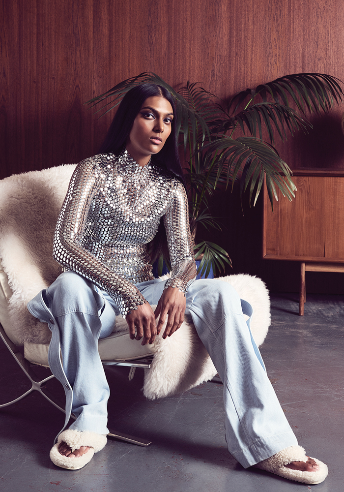 من "بربري" Burberry، قميص طويل مكسو بالترترة الفضية، وسروال من الدنيم بقصة فضفاضة، وشبشب مفتوح مكسو بالفرو الاصطناعي.