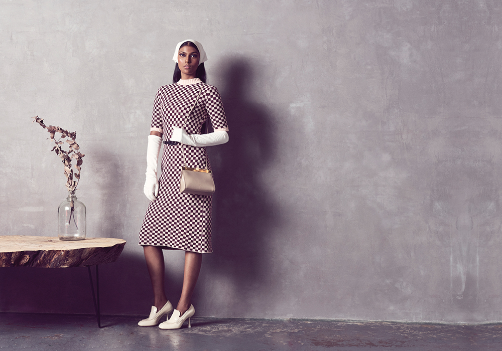 من "سبورتماكس" Sportmax، فستان محبوك ومزخرف بنقشة مربعات، وحزام أسود رفيع، وقفازات جلدية كريمية اللون، ووشاح رأس جلدي، وحذاء "لوفر" عالي الكعب من الجلد اللماع الكريمي اللون، وحقيبة كتف من الجلد.