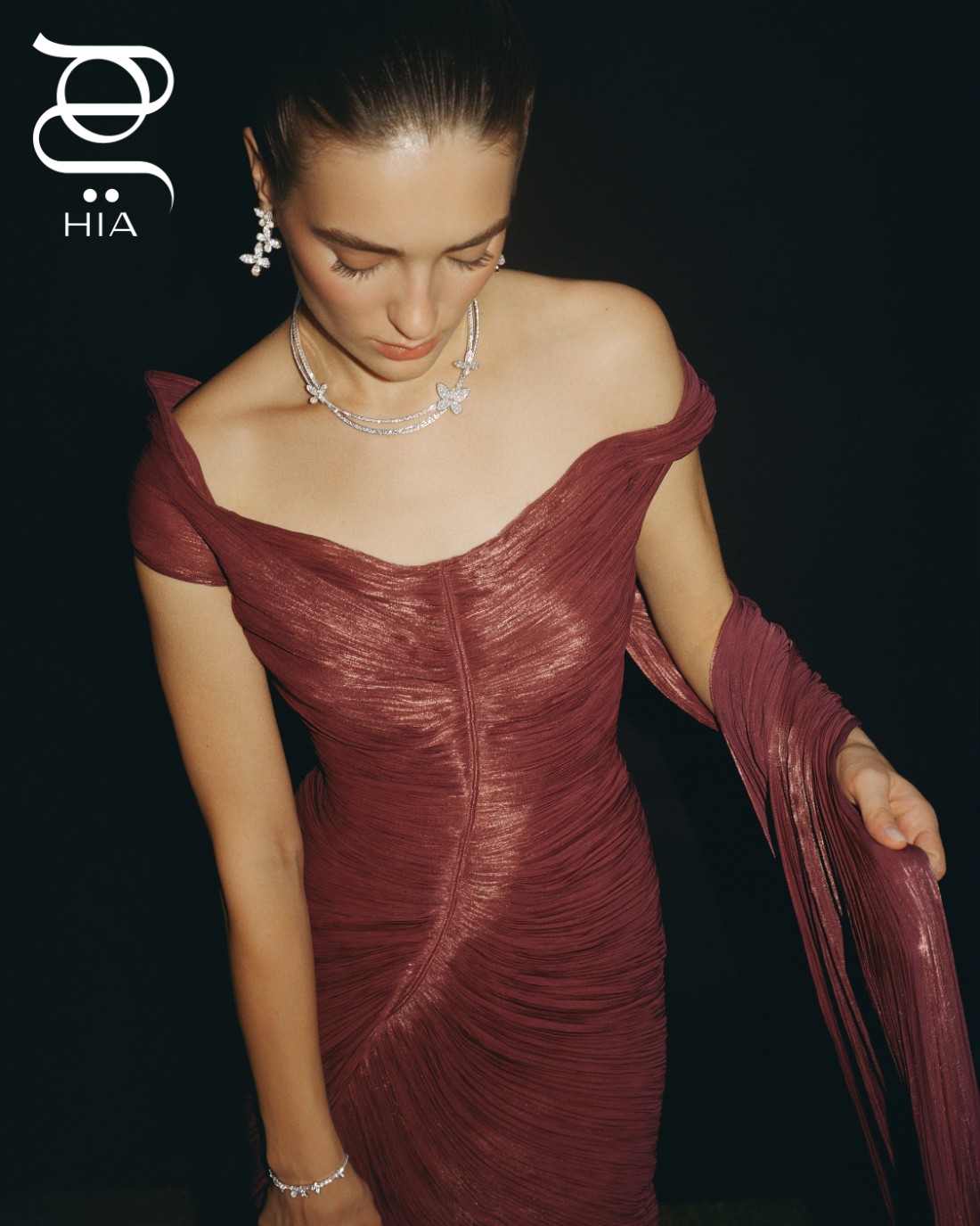 من مجموعة PAVÉ BUTTERFLY: أقراط أذن بثلاثة موتيفات فراشة من الذهب الأبيض المرصوف بنحو 5 قراريط من الماس، وعقد من الذهب الأبيض المرصوف بنحو 15.64 قيراط من الماس، وسوار من الذهب الأبيض المرصوف بنحو 3.31 قيراط من الماس، وخاتم من الذهب الأبيض المرصوف بنحو 1.15 قيراط من الماس جميع المجوهرات من "غراف" GRAFF فستان من "مرمر حليم" MARMAR HALIM