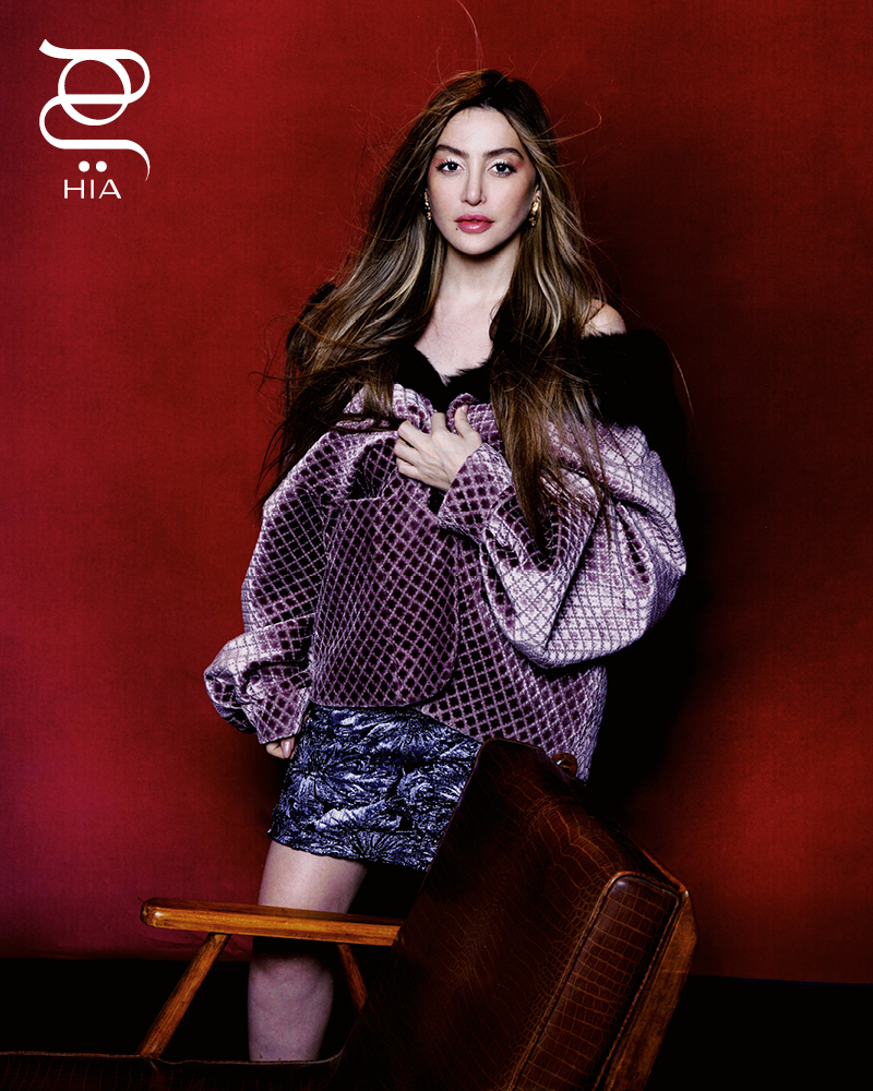 معطف "كابان" Caban من مخمل الجاكار الليلكي ومزدان بتطريزات تنورة ميدي بقصة قلم من قماش "لامي كلونيه" lamé cloquet مزينة بزهور باللون الليلكي أقراط مطلية بلمسات ذهبية جميعها من دار "غوتشي" GUCCI