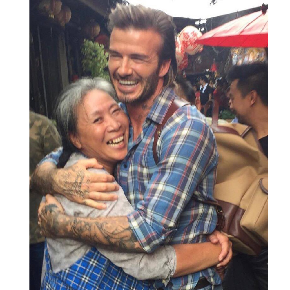 صورة طريفة لديفيد بيكهام محتضنا إحدى السيدات التايلنديات خلال زيارته الحالية لهناك