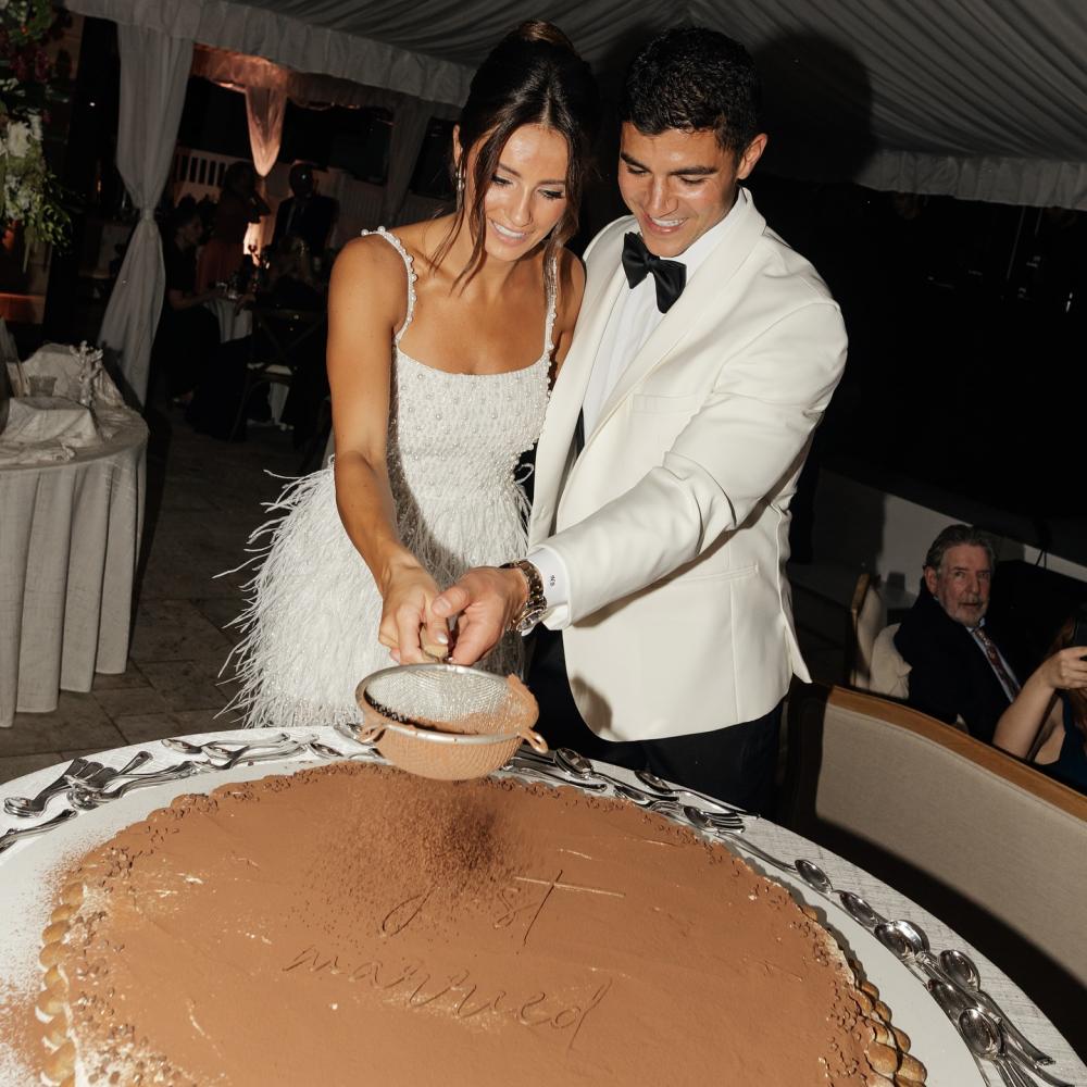 عروسان يقومان بتزيين الكيك مباشرة ليلة الزفاف أمام الضيوف