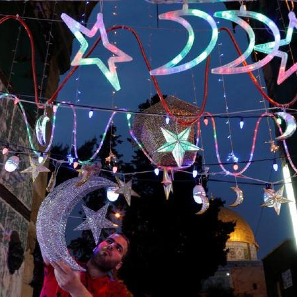 شاب فلسطيني يعلق زينة رمضان احتفالا بقدوم الشهر الكريم في القدس