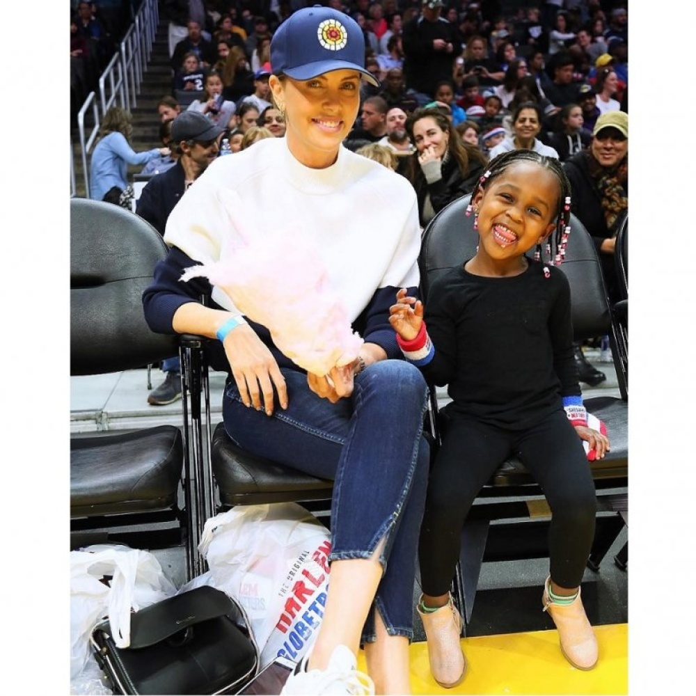 تشارليز ثيرون تبتسم للكاميرا مع ابنتها أوغست أثناء حضورهما مباراة لكرة السلة