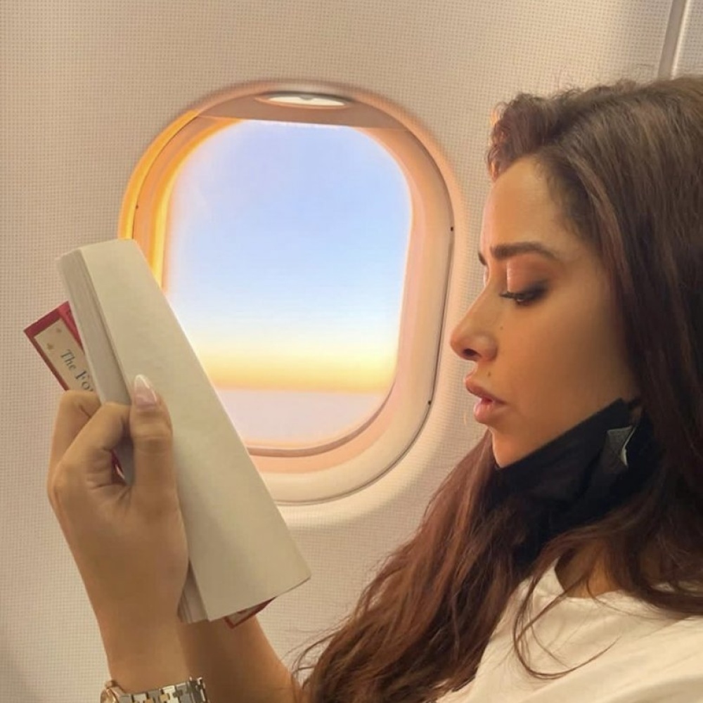 بلقيس فتحي تستمتع بقراءة كتابها الجديد خلال رحلتها في الطائرة