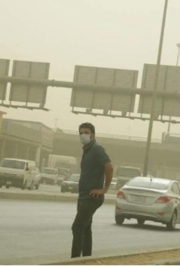 أحد المواطنين يحاول عبور الشارع وسط الغبار 