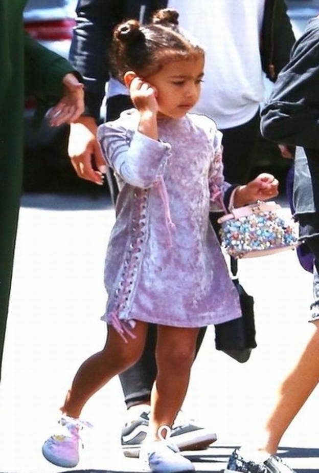 اطلالة رائعة لنورث ويست في فستان قصير من المخمل مزين لربطات جانبية نسقته مع شنطة يد من فندي وحذاء رياضي ملون