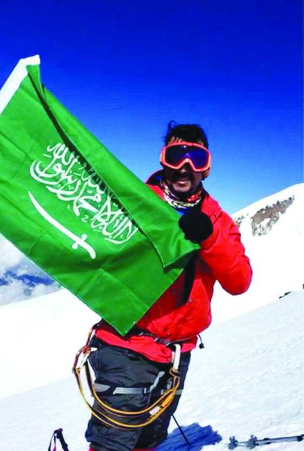 خالد الغامدي يرفع علم المملكة وعلم الرؤية 2030.