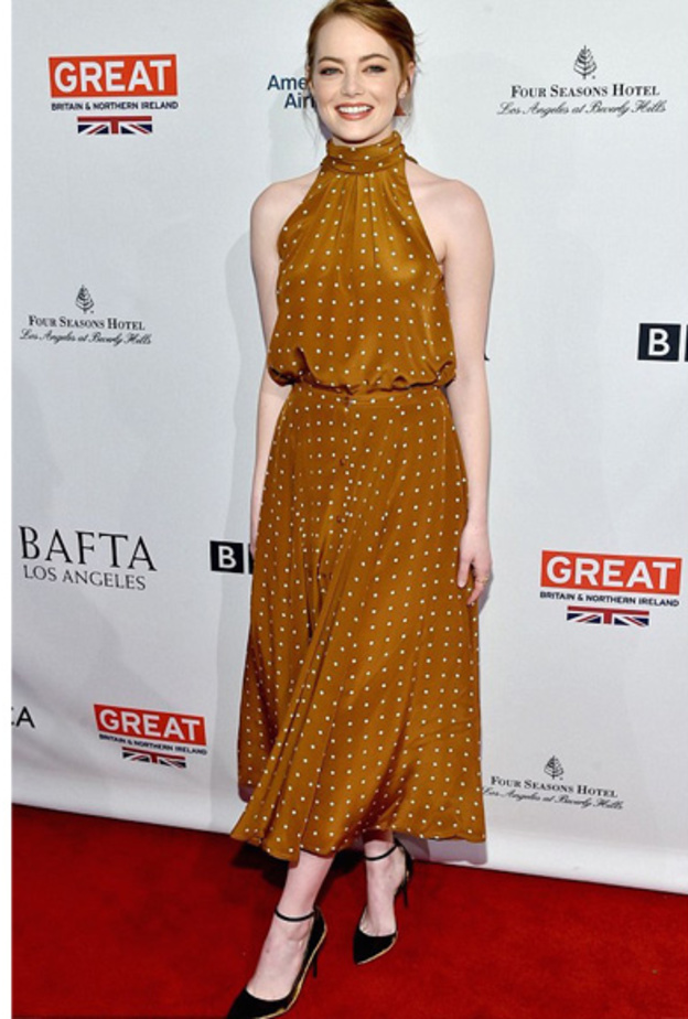 اختارت ايما ستون فستانا أنثوي بلون الأورانج الخردلي ونقشة البولما بالأبيض