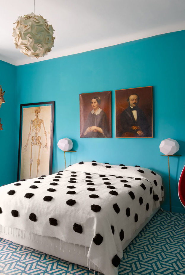 الكرسي باللون الأحمر يبرز بتناغم مع الستارة و غطاء السرير بالأبيض و الأسود