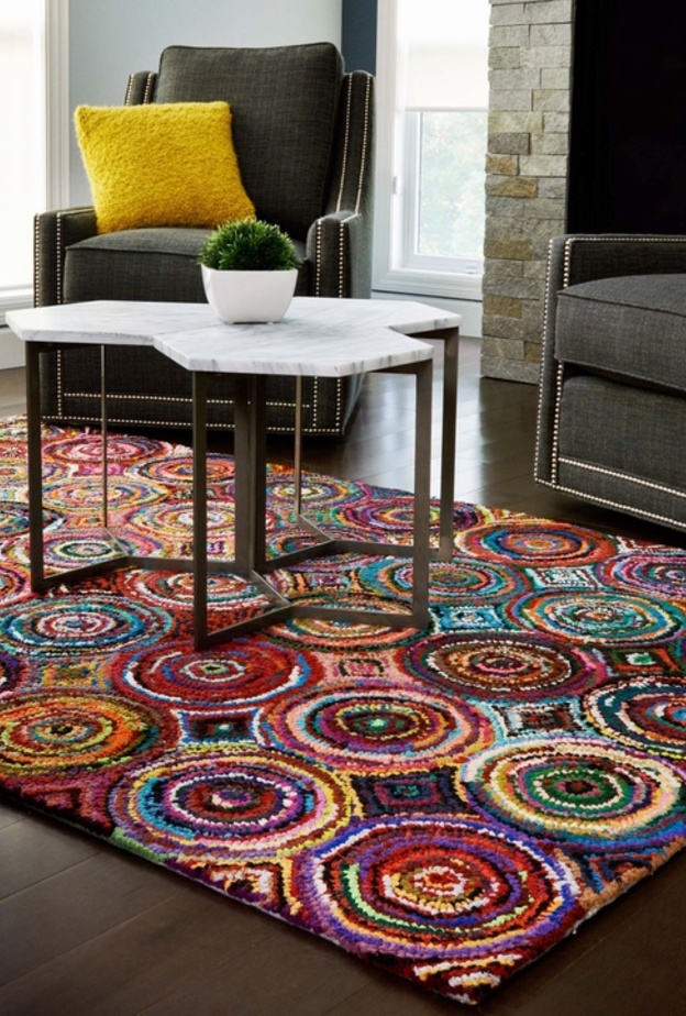 على الأرضية الخشب و اللون الرمادي للكنب لا شيء أجمل من سجادة ملونة بألوان مشرقة